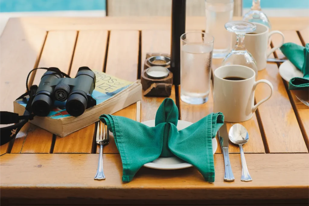 Birder's breakfast setting with binoculars and field guide by the pool at Tanager Rainforest Lodge.